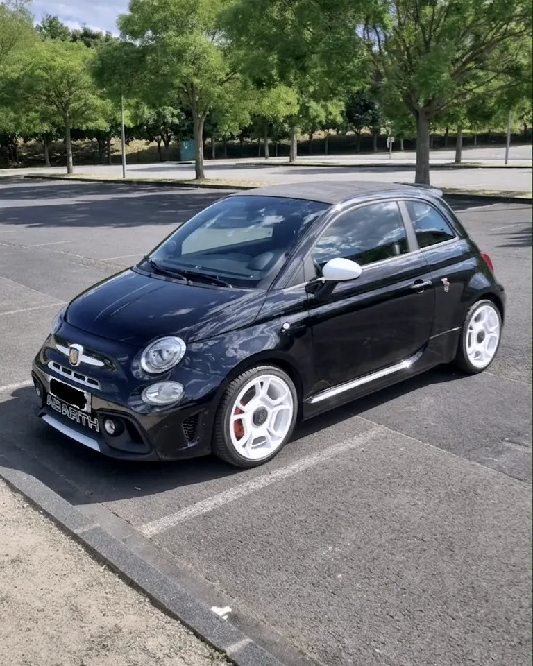 La Fiat 500 Abarth noire de Julien, co-fondateur de TokDrive, garée sur un parking bordé d'arbres